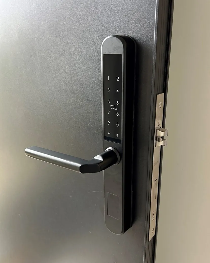 Dark slimline smart lock fitted to a grey aluminium door